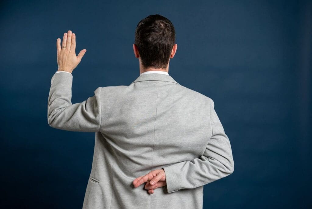 A man in grey jacket holding his hand up to the side.